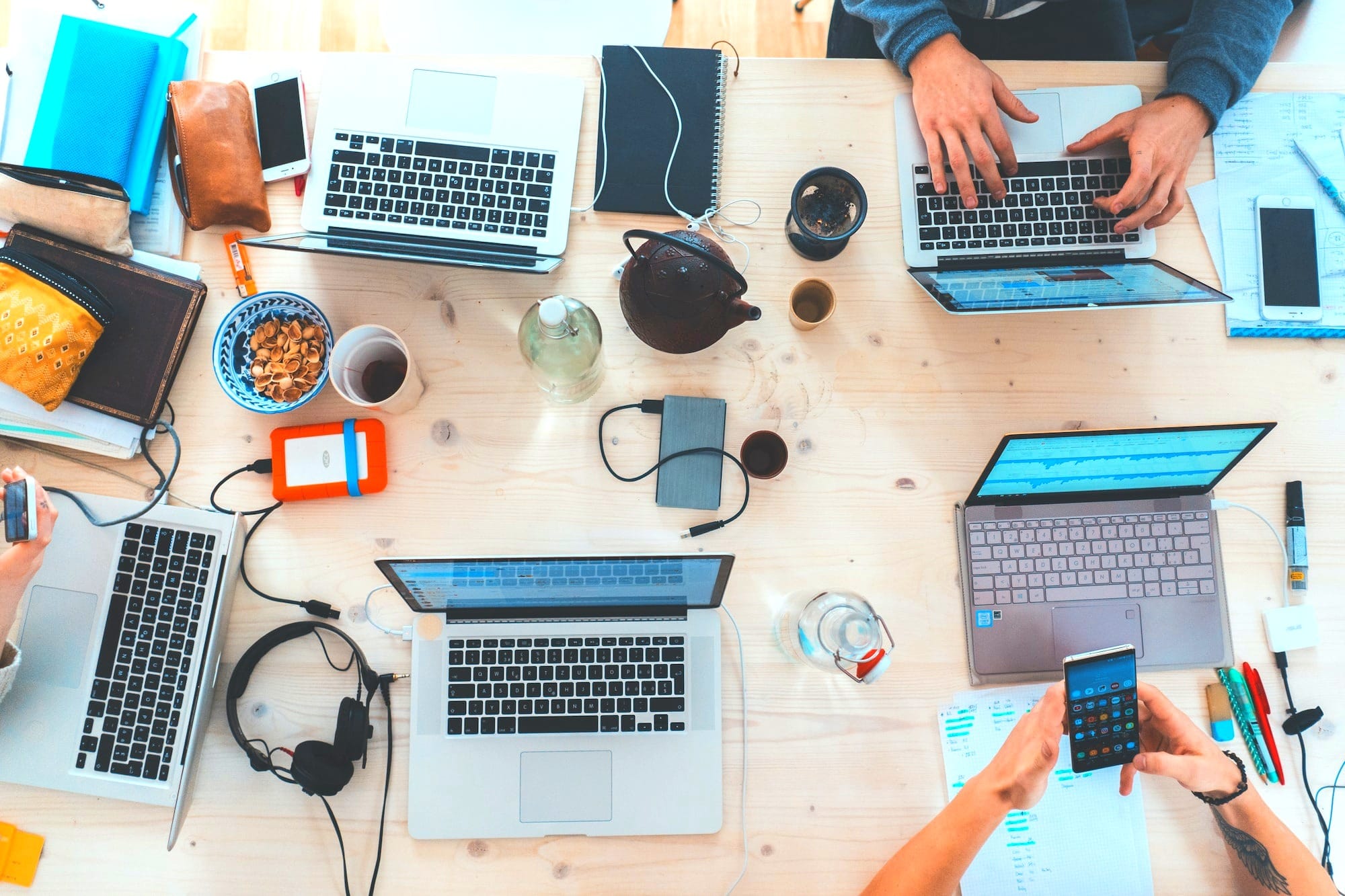 people sitting down near table with assorted laptop computers