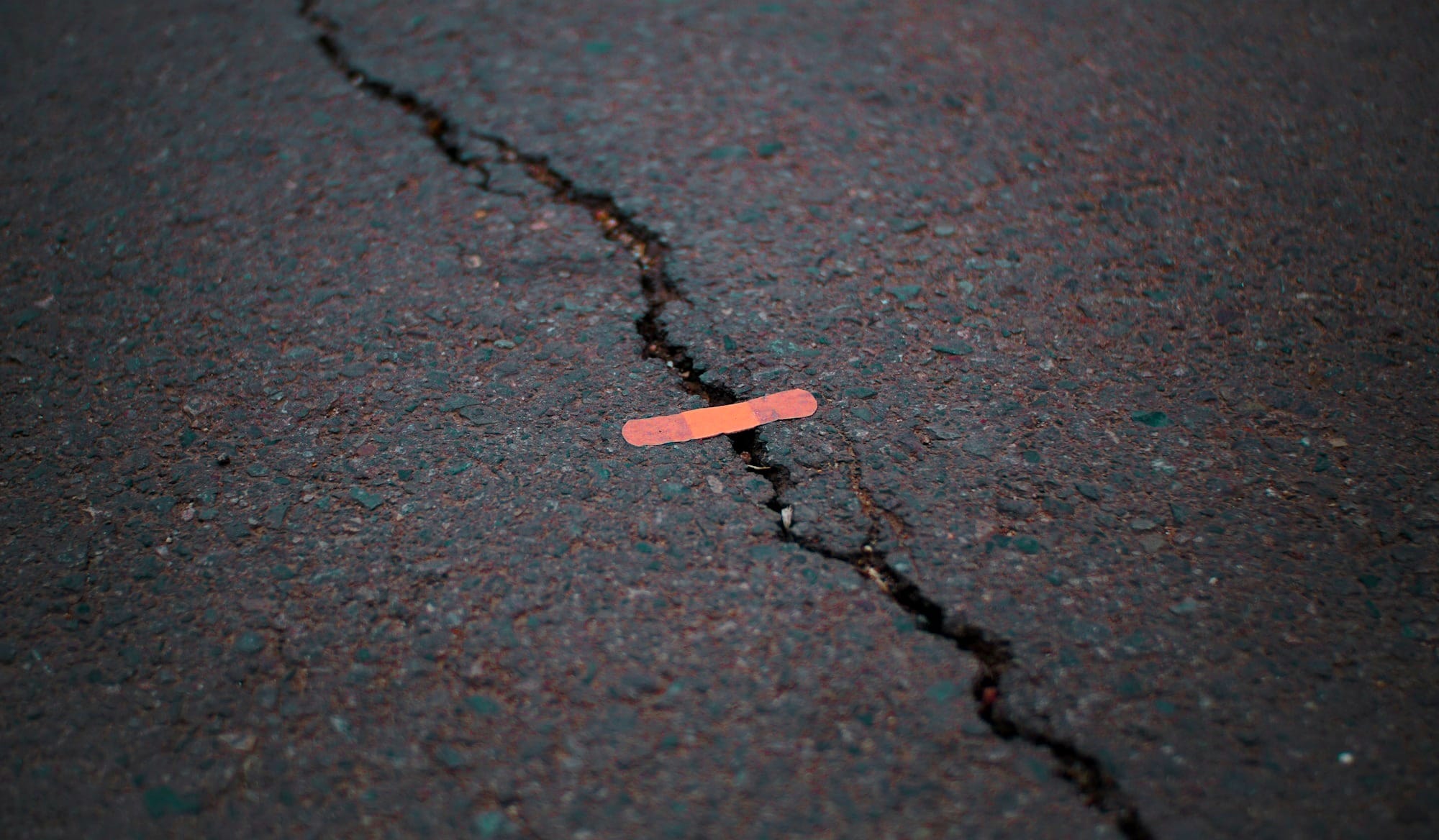 orange band aid on concrete surface crack